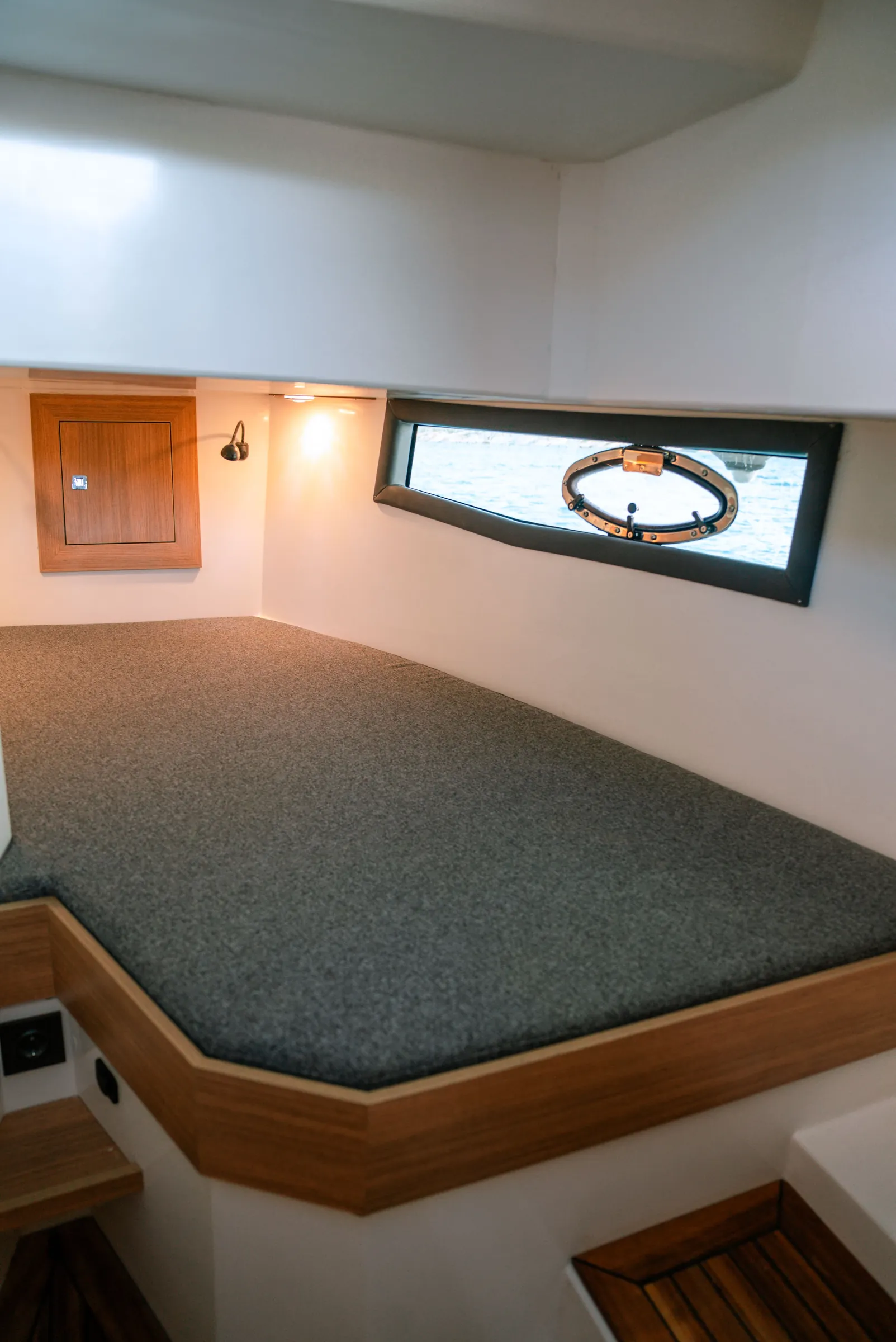 A double berth in the cabin, wood trim, a long window with an oval portlight